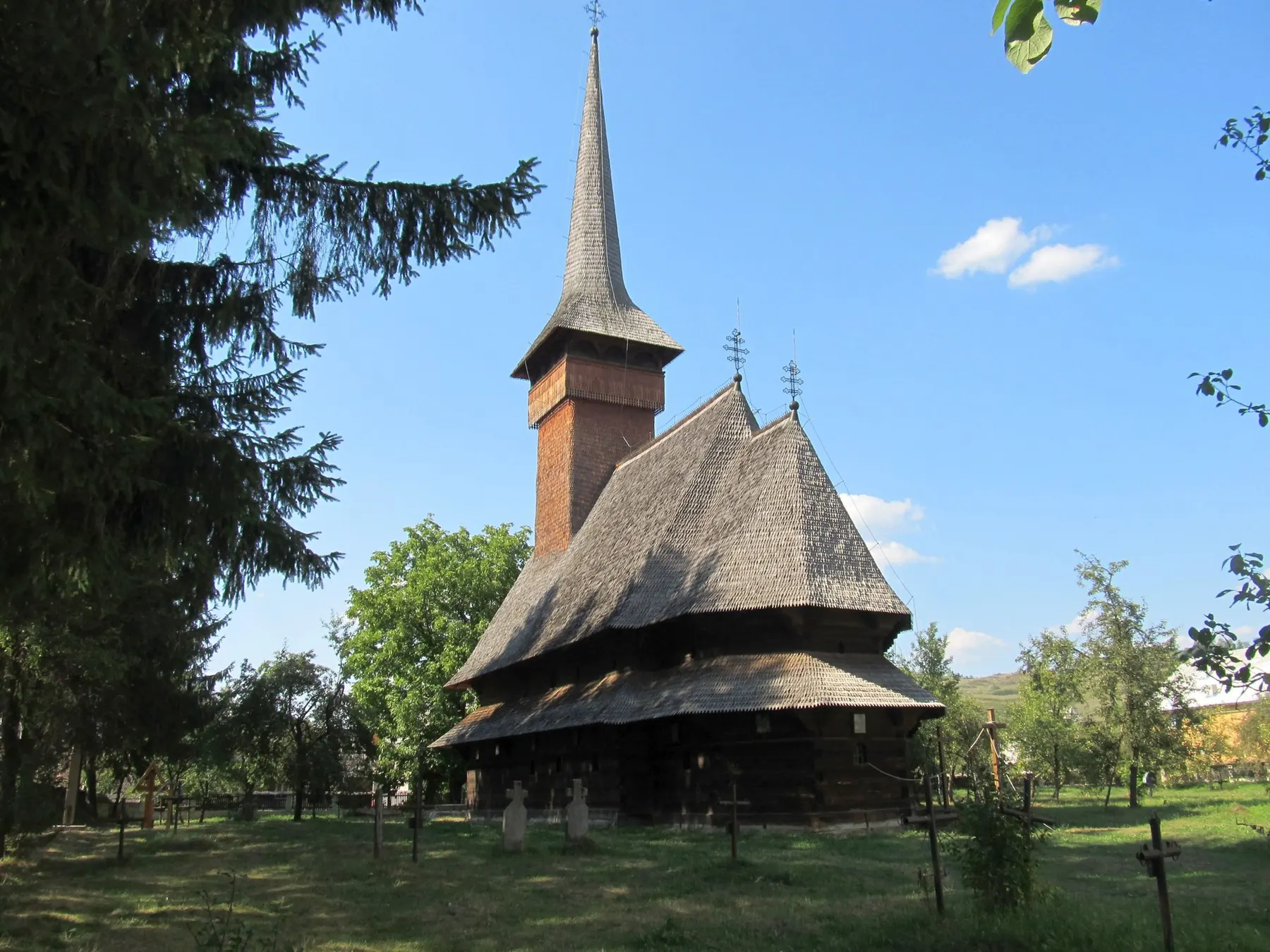 Biserica de lemn Sfântul Nicolae din Bogdan Vodă, cu turn zvelt, în cimitirul vechi din mijlocul satului.