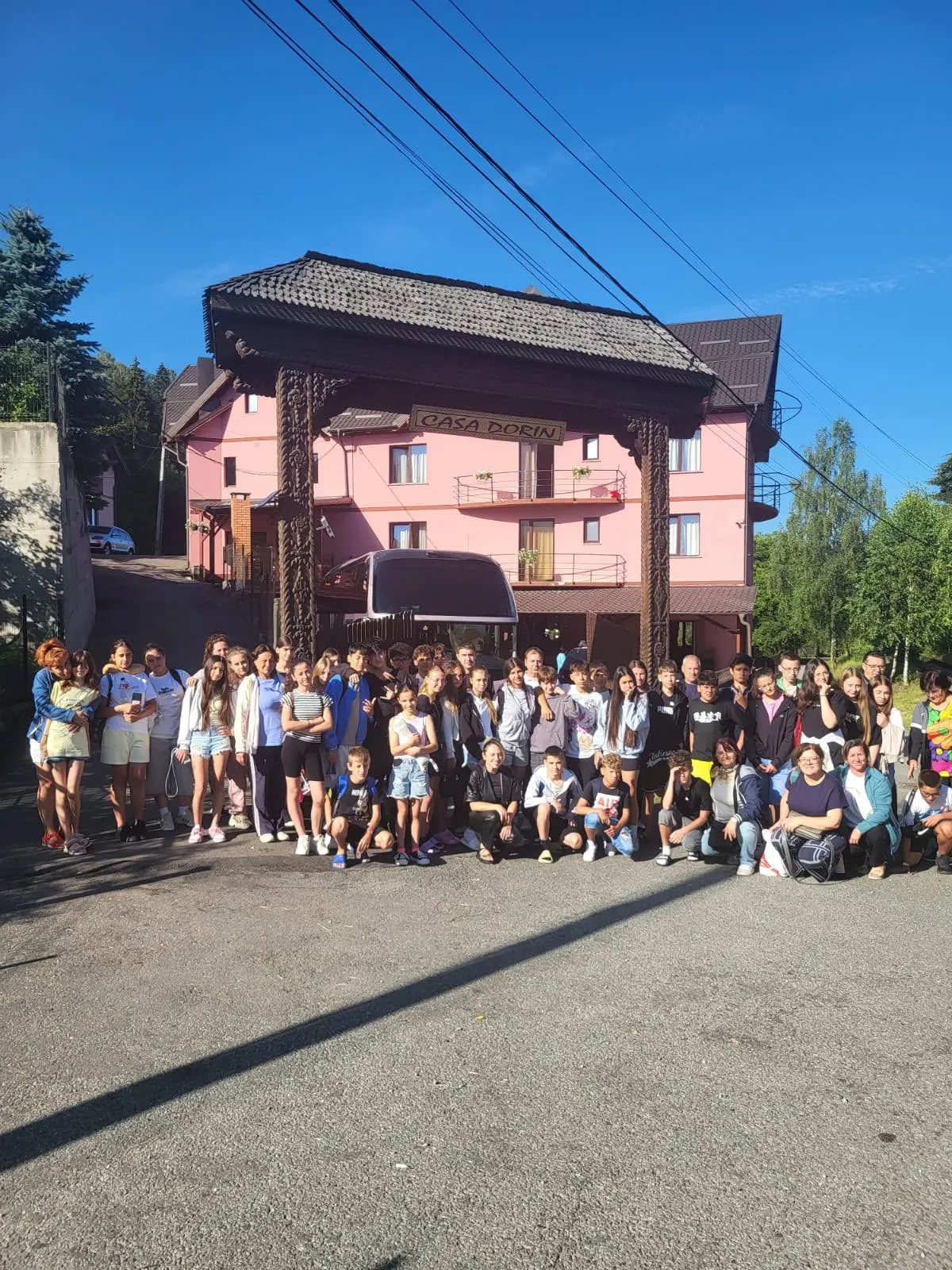 Grup școlar în fața pensiunii, cu autocarul în spate.