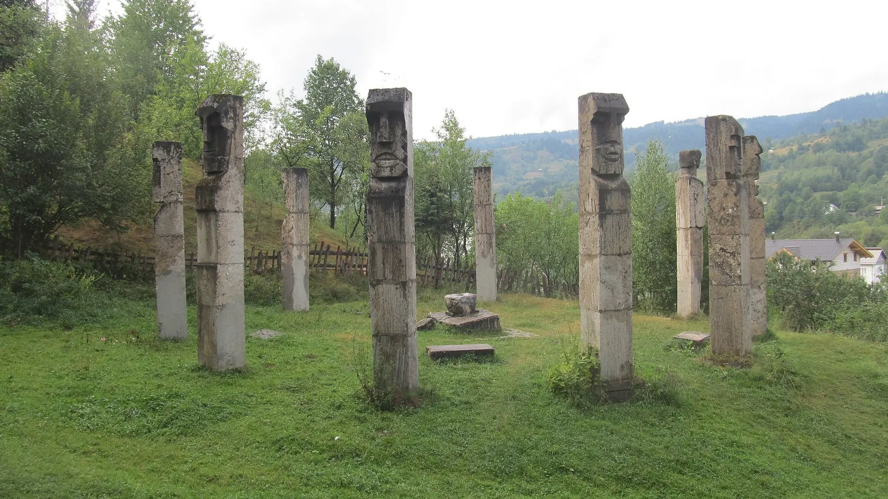 Monumentul Eroilor de la Moisei: stâlpi înalți de piatră sculptată, așezați în cerc pe o pajiște.