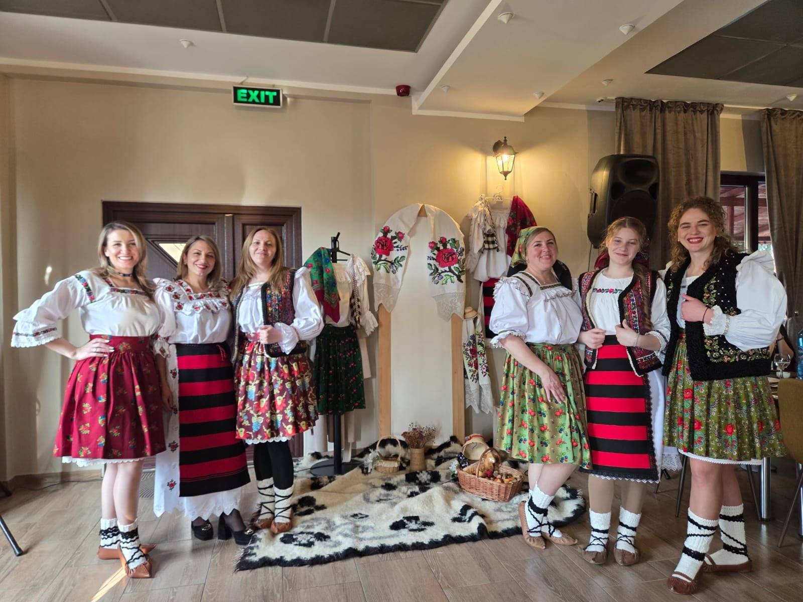 Șase oaspete în costume tradiționale maramureșene, în sala de mese.