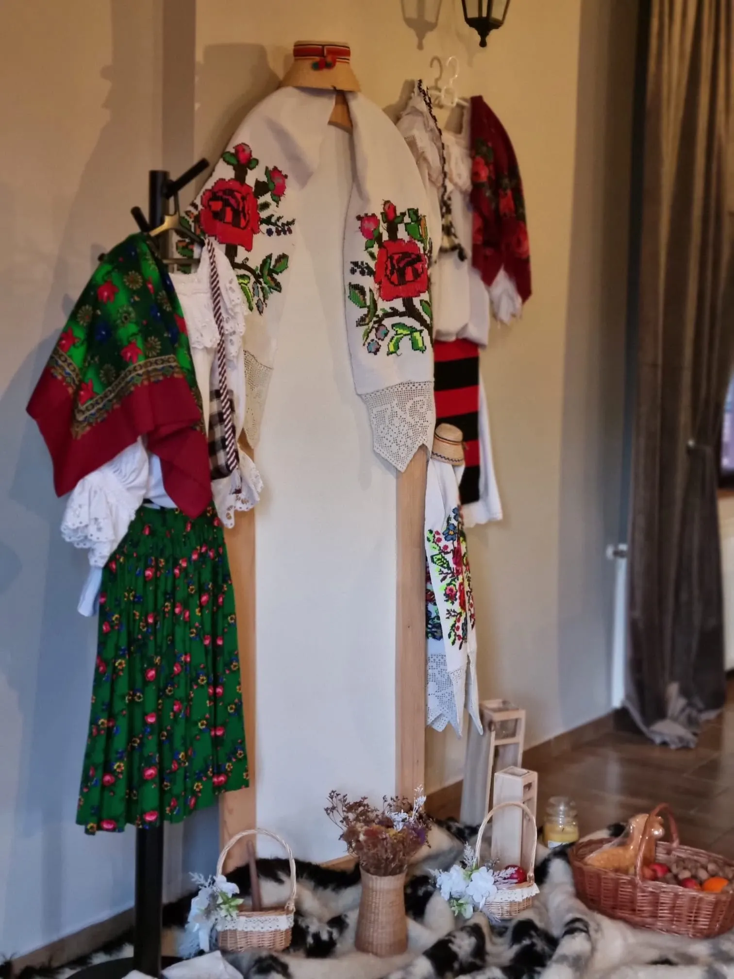Costum popular maramureșean expus în holul pensiunii, lângă coșuri și blănuri.