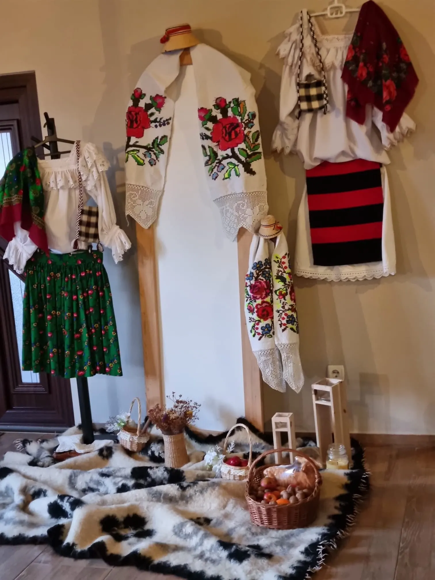 Costume populare maramureșene expuse în pensiune: cămăși cusute, fote vărgate și șorțuri.