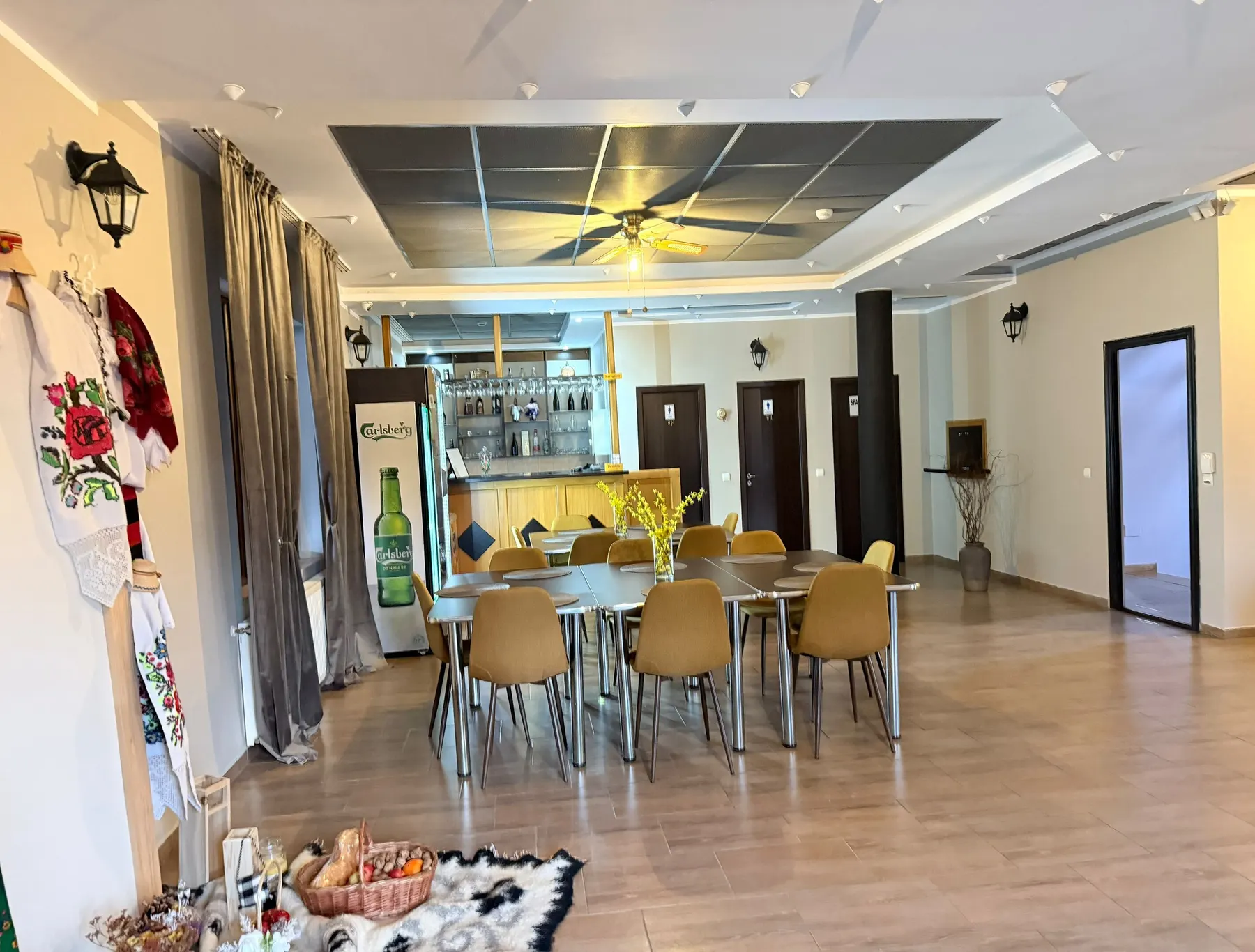 Sala de mese luminoasă, cu costum popular maramureșean la intrare și mese așezate pentru grup.