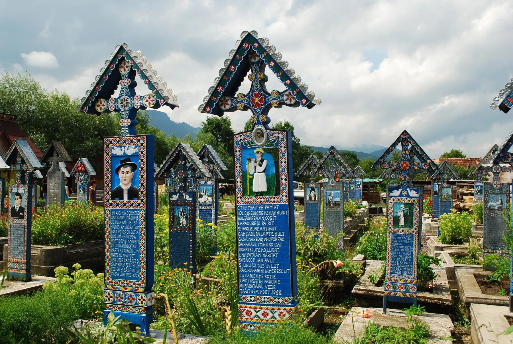 Cruci sculptate și pictate în Cimitirul Vesel, cu portretul și versurile celui înmormântat.